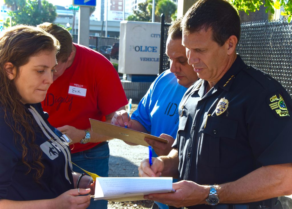 Orlando Police Chief, John Mina helps an IDignity client get her queue card filled out.