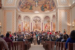 Almost 100 people each hold a candle.