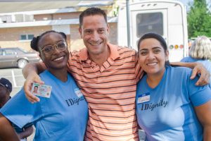 A happy IDignity client celebrates getting his new ID with two volunteers.