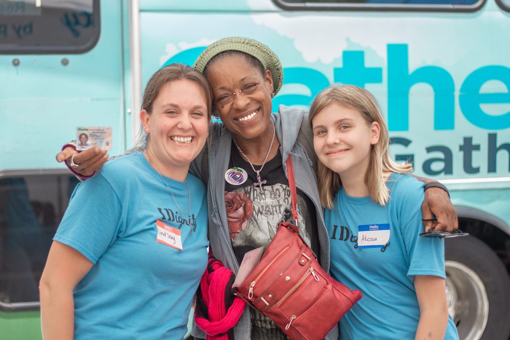 Two volunteers pose with an ecstatic client and her new ID