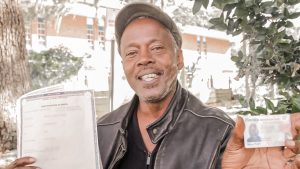 An IDignity client shows off his new ID and Birth certificate